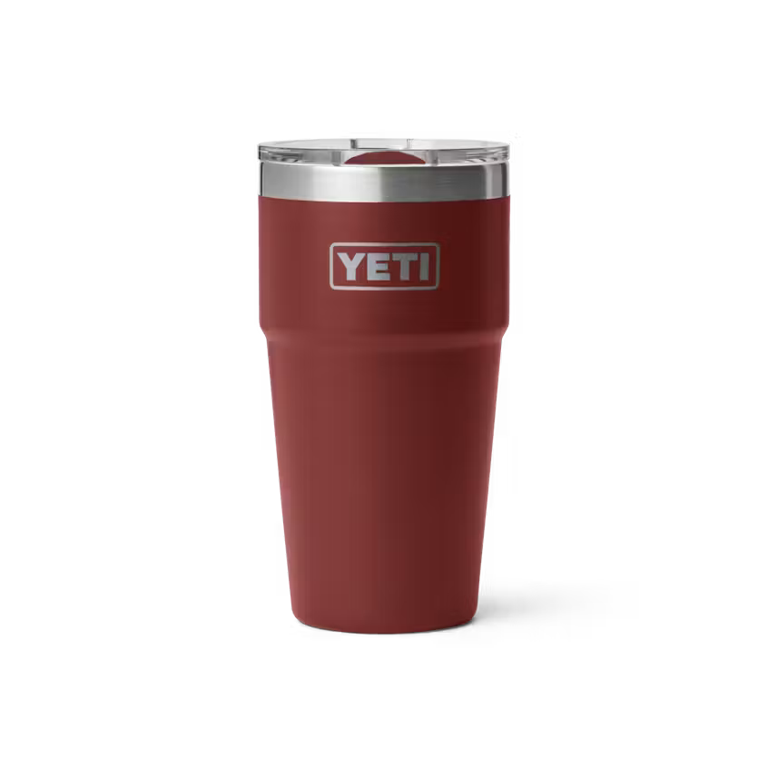 A YETI insulated travel tumbler in matte dark red with a stainless steel rim and a clear lid, shown on a clean white background.